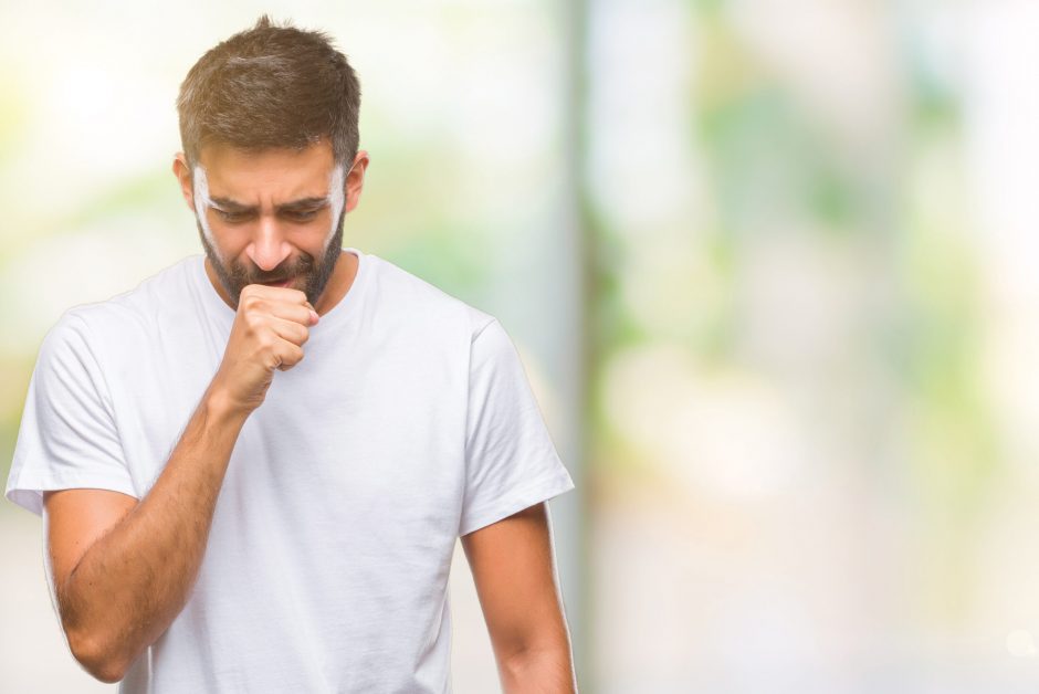 Adult hispanic man over isolated background feeling unwell and coughing as symptom for cold or bronchitis. Healthcare concept.